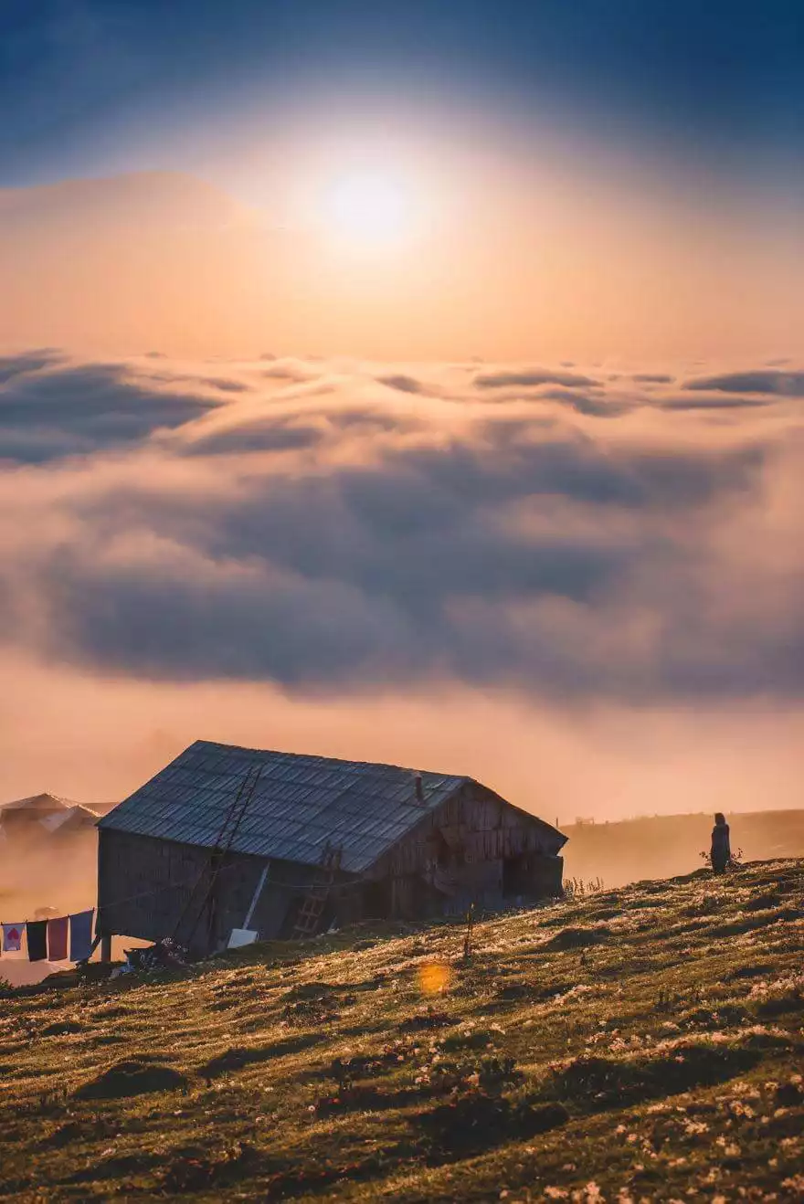 Houten huisjes boven een zee van wolken op Gomi Mountain, Georgië