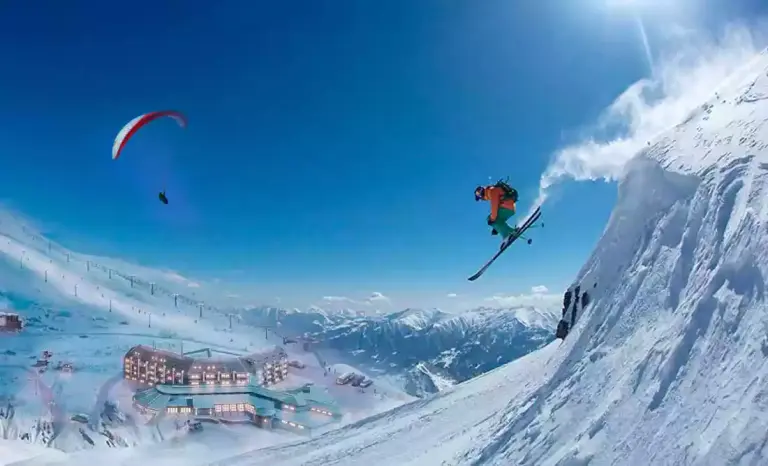 Een skiër en een paraglider boven het skidorp