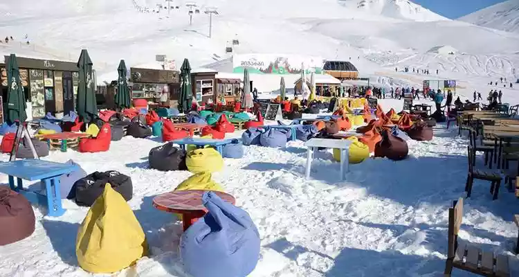 Zitzakken en terrastafels in de sneeuw onder aan de piste in Gudauri