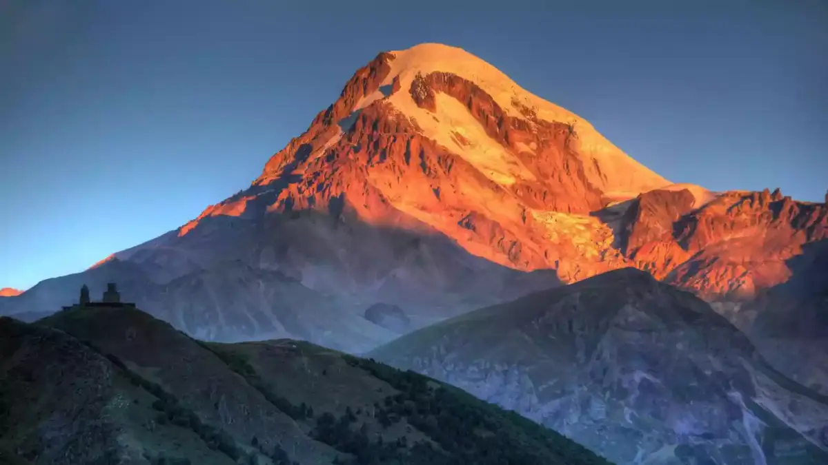 De Kazbek in avondlicht boven het dal van Stepantsminda