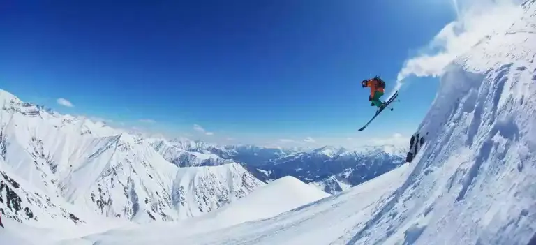 Een freerider springt van een sneeuwrichel boven het dal