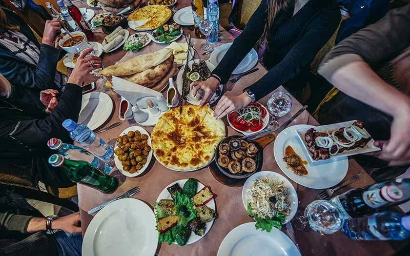 Een volle tafel met Georgische gerechten en handen die opscheppen
