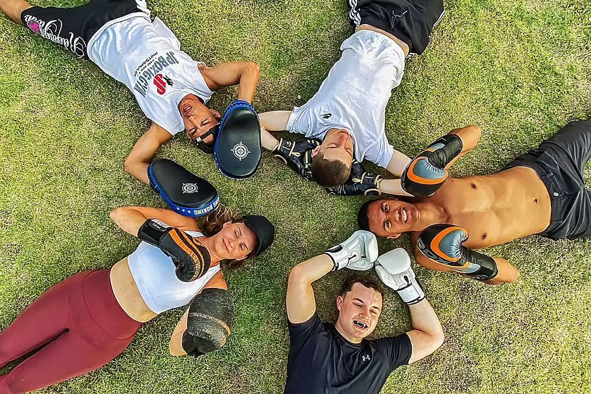 Vijf sporters liggen na de training in een kring uit te rusten in het gras