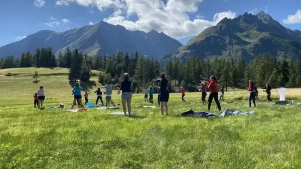 Groep sport samen op een bergweide, met de Kaukasuskammen op de achtergrond
